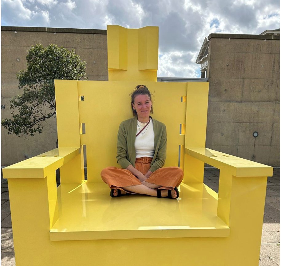 a person sitting crosslegged on a gigantic yellow chair
